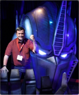 Standing in the hand of Optimus Prime, from the Hasbro exhibit at San Diego Comic-Con, promoting Transformers Prime on the Hub network.